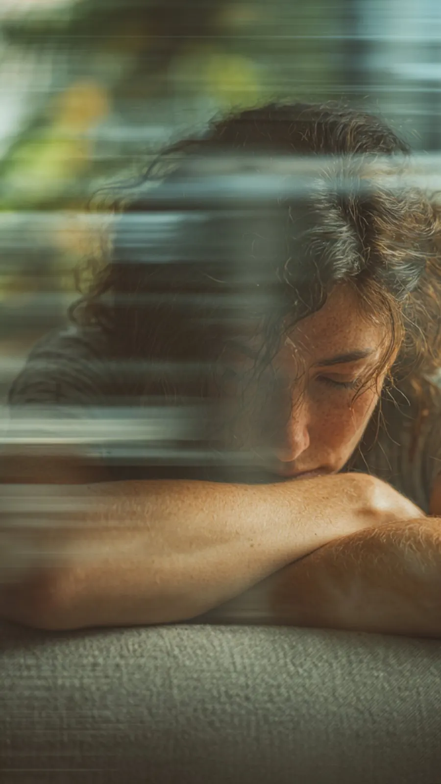 A person rests their head on their arms with a blurred visual effect, symbolizing the overwhelming racing thoughts and mood shifts associated with bipolar disorder.