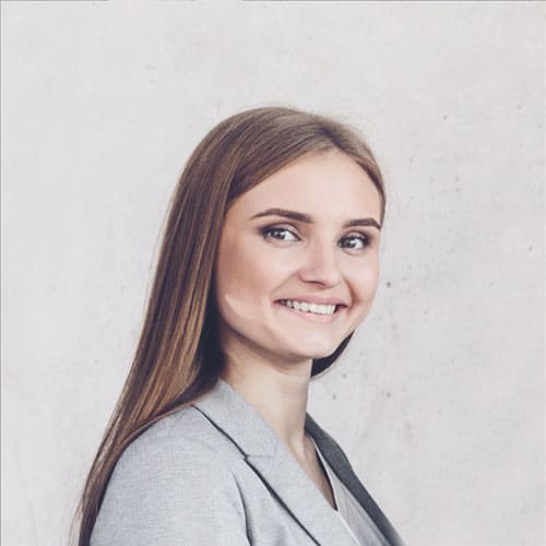 A smiling professional woman in a grey blazer, representing the dedicated and approachable mental health staff at Serenity Grove.