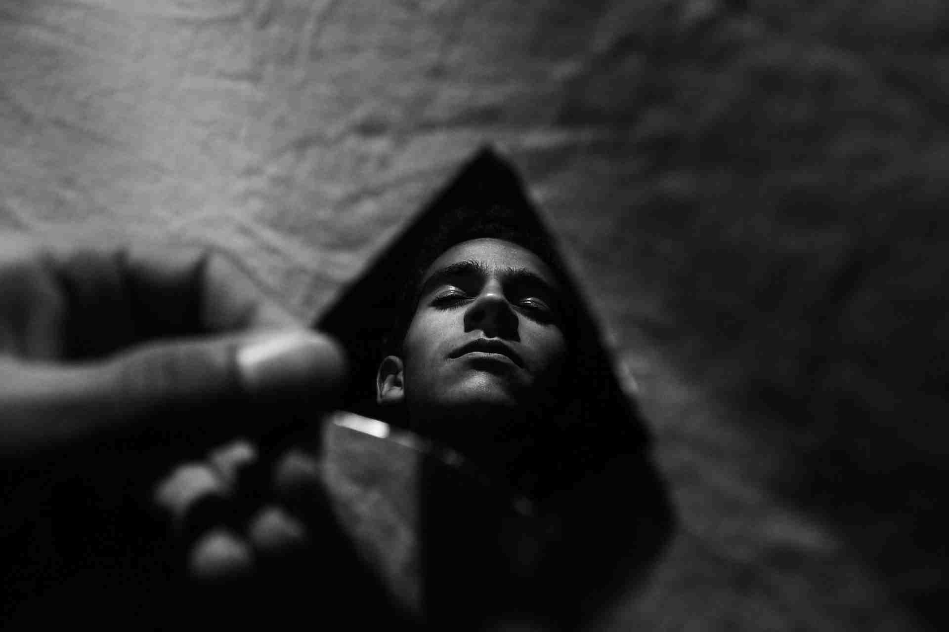 Black and white image of a person lying down with eyes closed, symbolizing anxiety, panic attacks, and emotional distress.