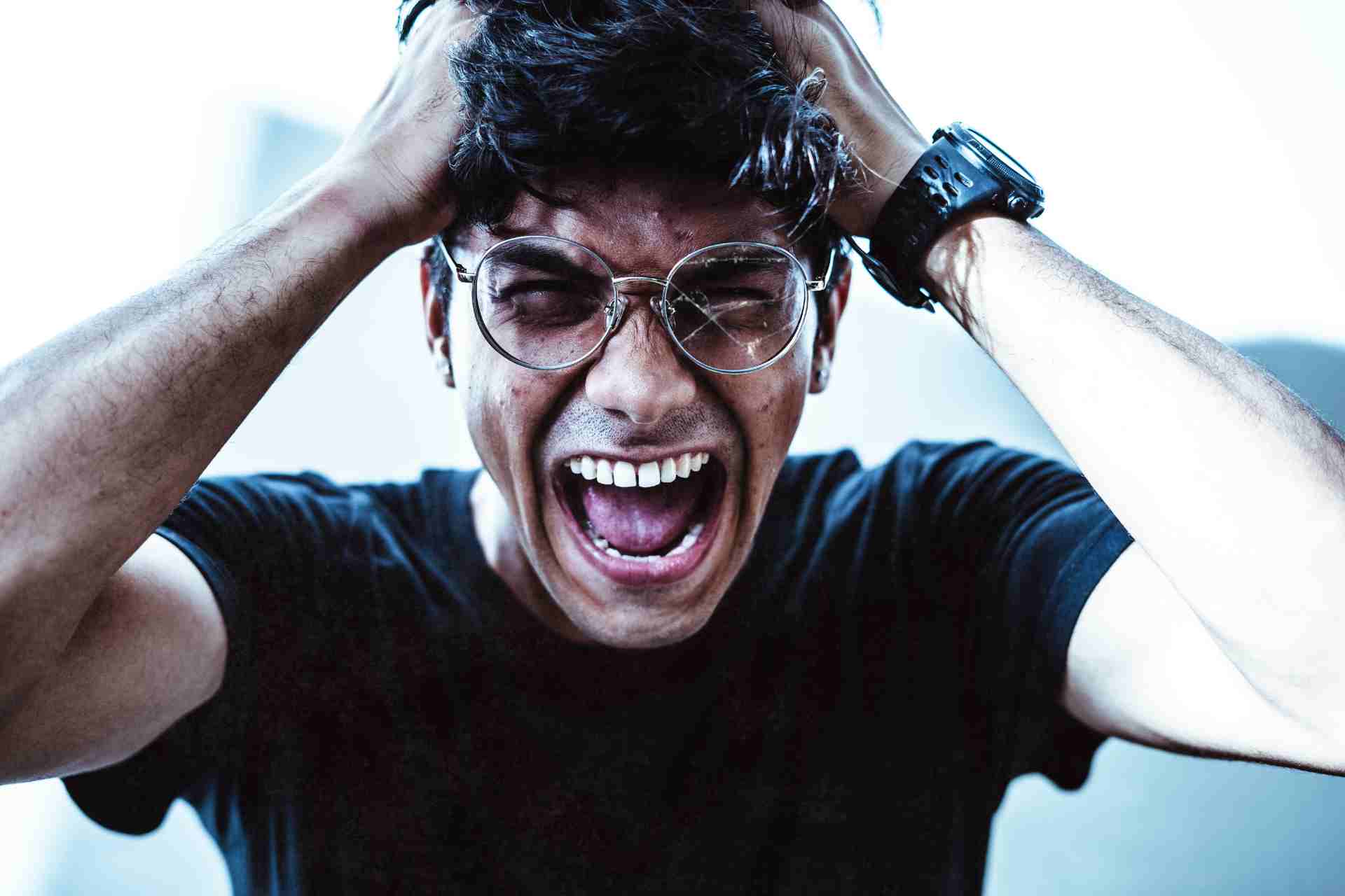 Young man experiencing intense anxiety and emotional stress while holding his head and screaming