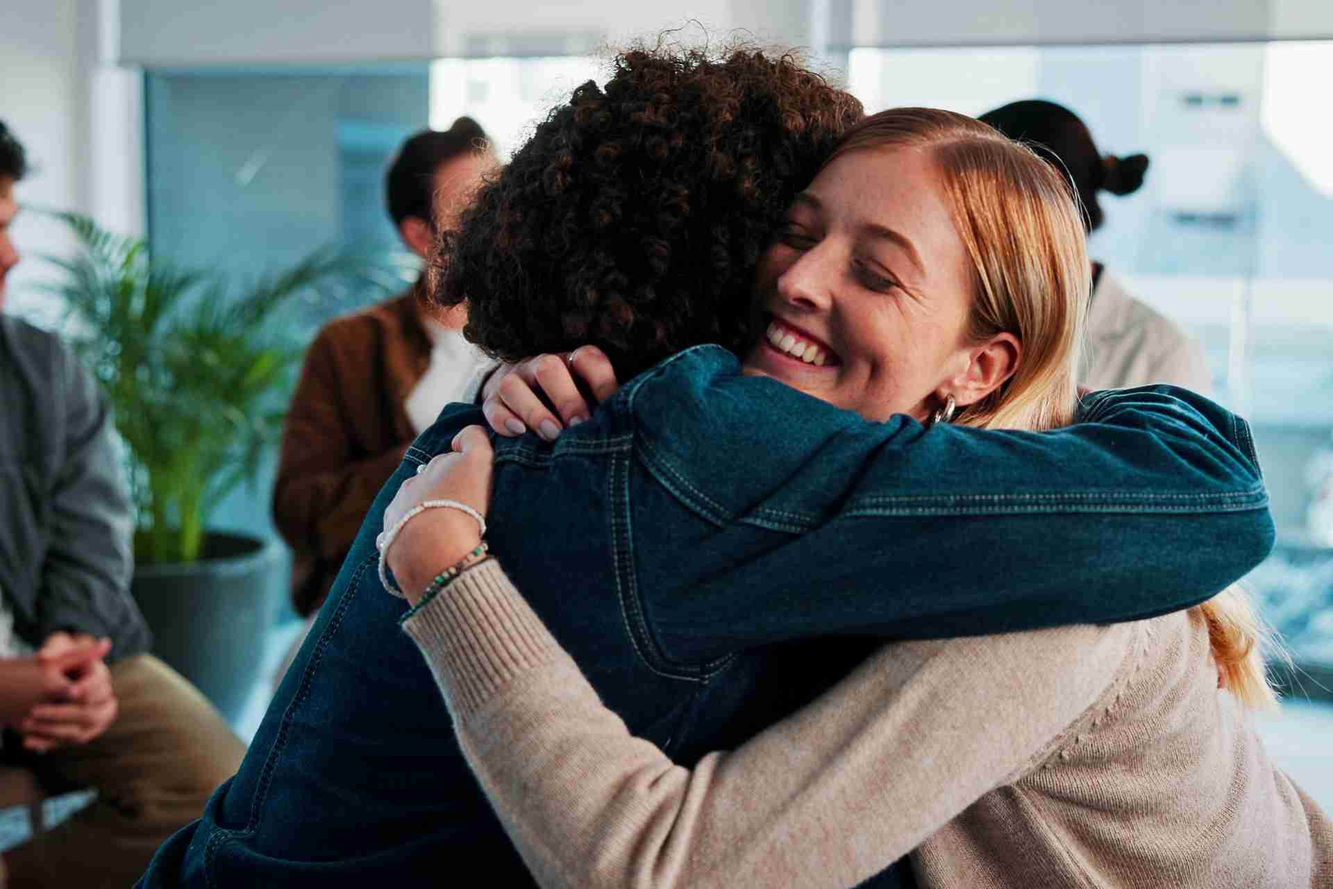 People embracing during a peer support and mental health recovery group session