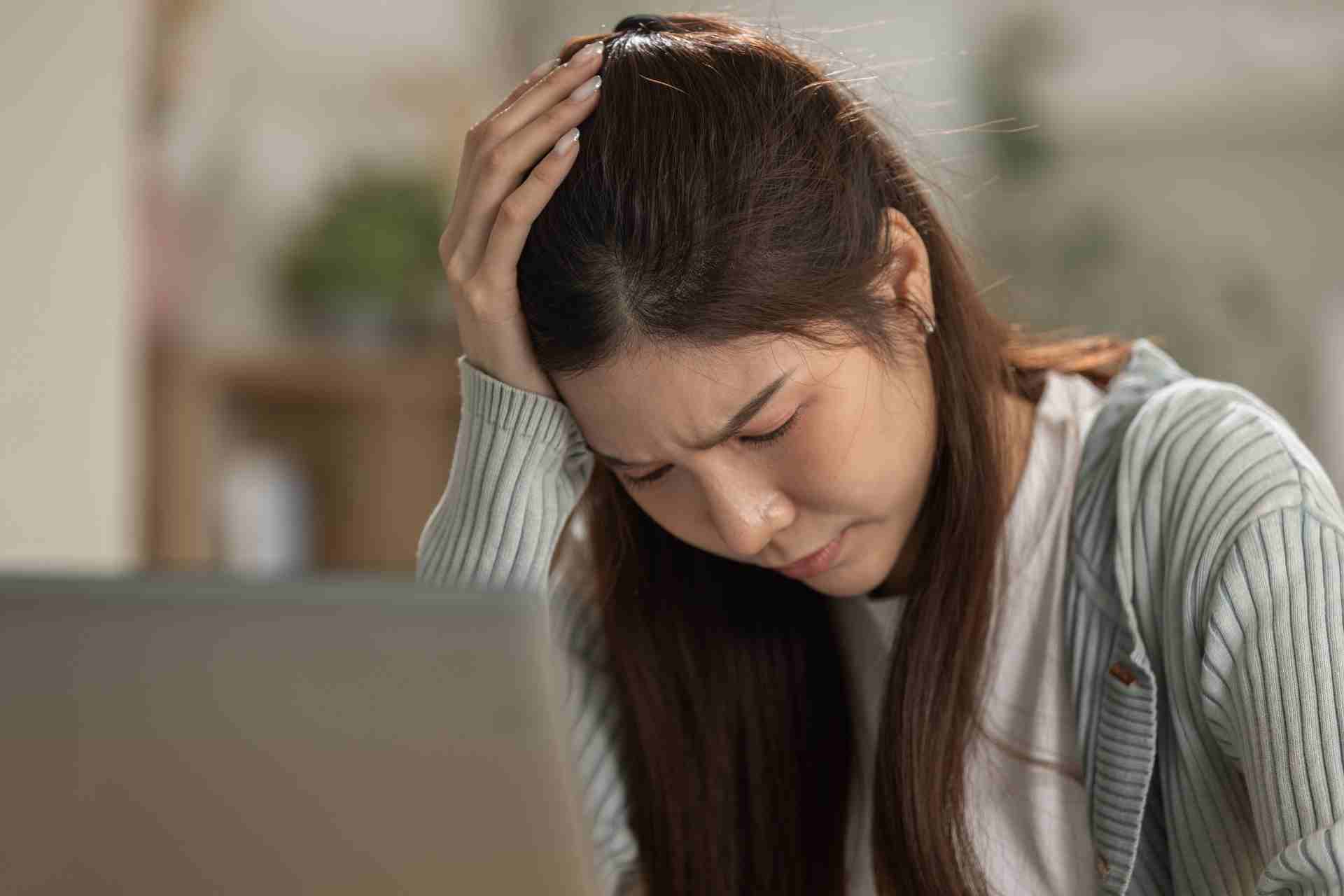 Woman experiencing emotional burnout and mental overwhelm while working on a laptop