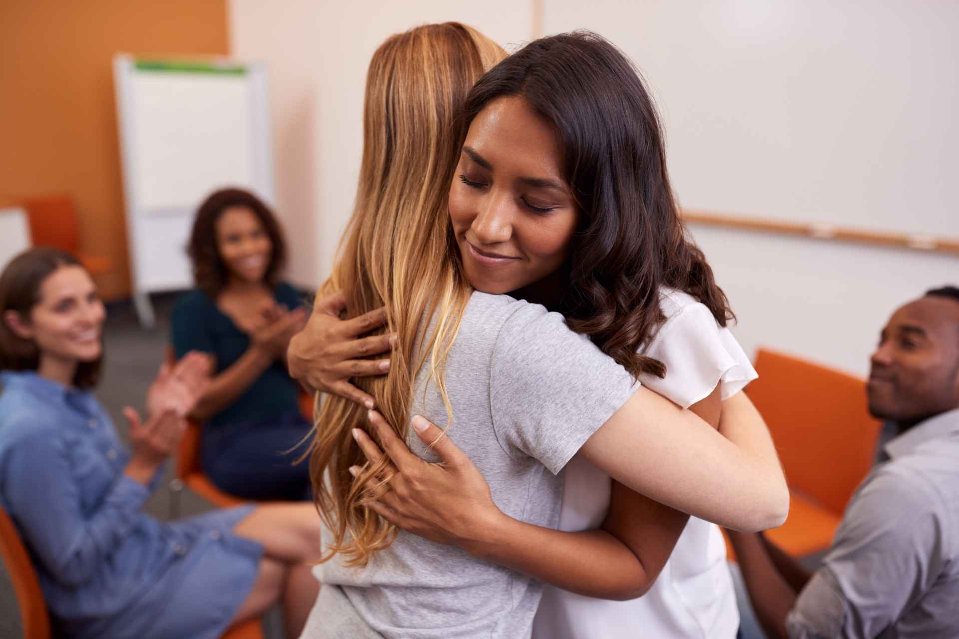 Two women hugging during a mental health recovery support group