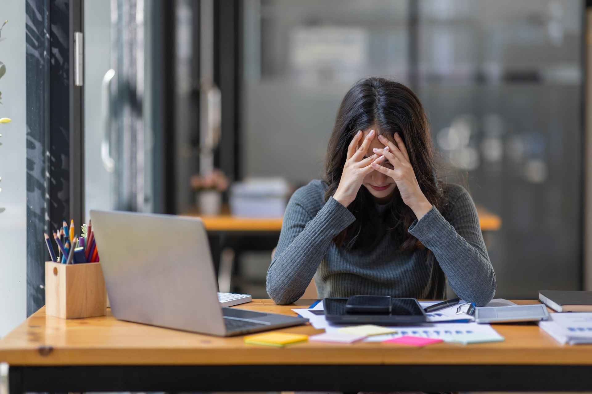 Woman feeling overwhelmed by chronic work stress at her desk