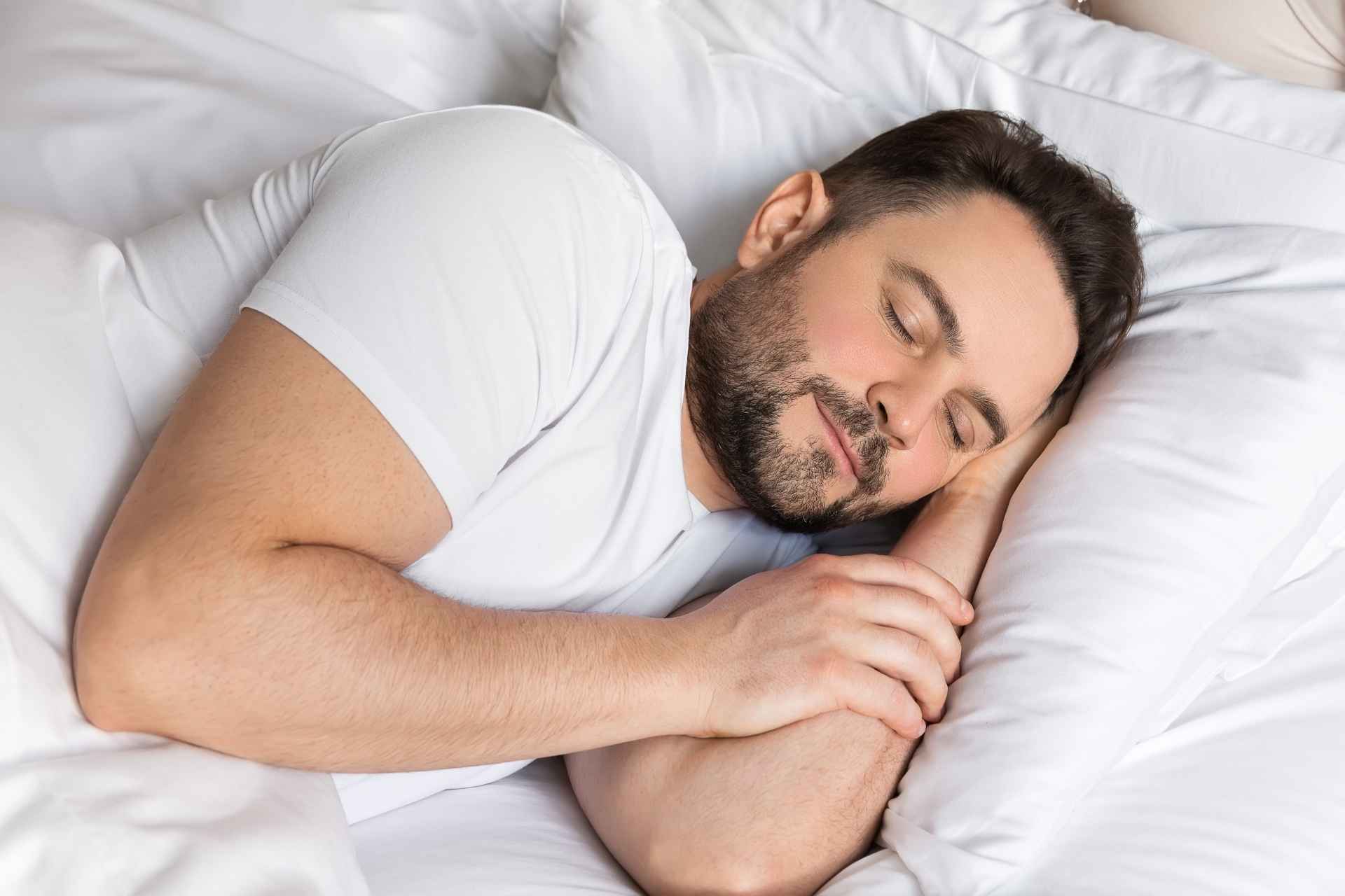 Man sleeping peacefully in bed as part of a healthy sleep routine